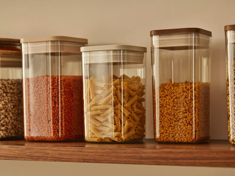 Contenants transparents remplis de pâtes, riz, lentilles et flocons d'avoine sur une étagère